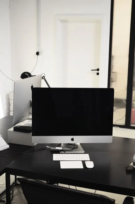 Gros plan sur des mains en train de taper sur un ordinateur portable, à côté d’une tasse de café posée sur un bureau en bois.